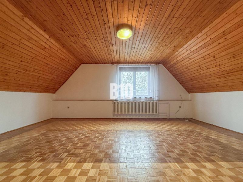 Attic room in a family house with a wooden ceiling and a floor with a wooden decor.