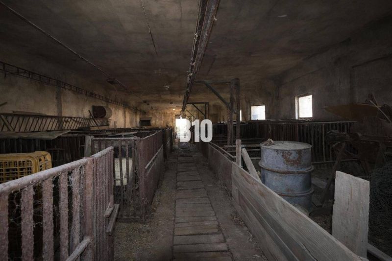 Old production facilities with cages and barrels, darkened windows.