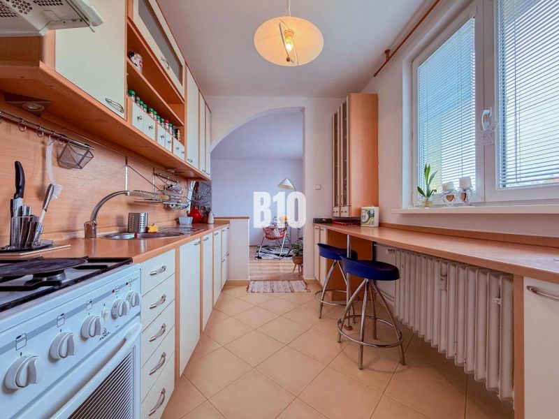 A kitchen in a 3-room apartment with a long work counter and a gas stove.