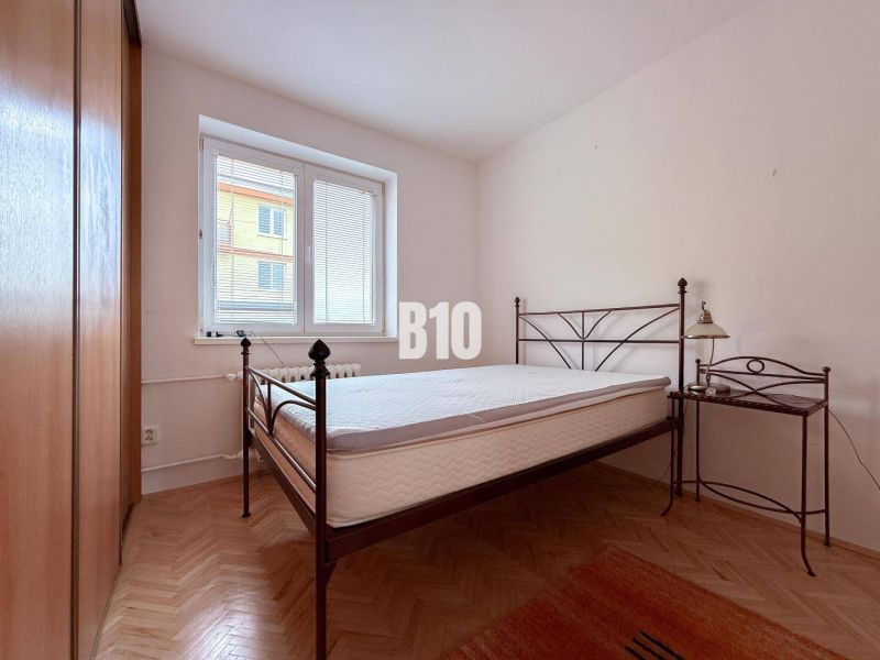 A bedroom in a 3-room apartment with a bed and a wooden decor floor.