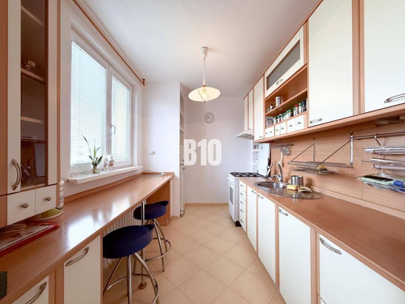 A bright kitchen in a 3-room apartment with bar stools and plenty of storage space.