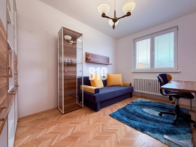 A room in a 3-room apartment with a wooden decor floor and a comfortable sofa.