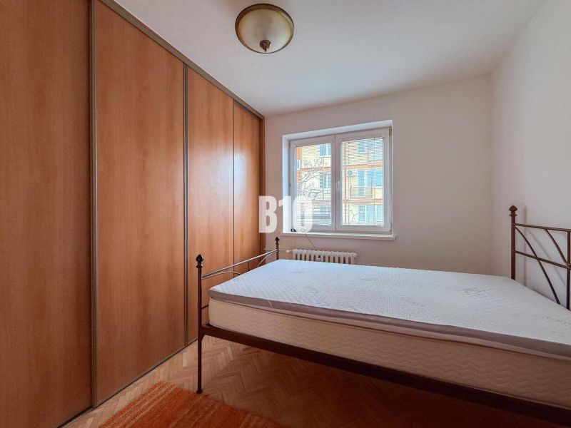 A bedroom in a 3-room apartment with a bed, built-in wardrobe, and flooring with a wooden decor.