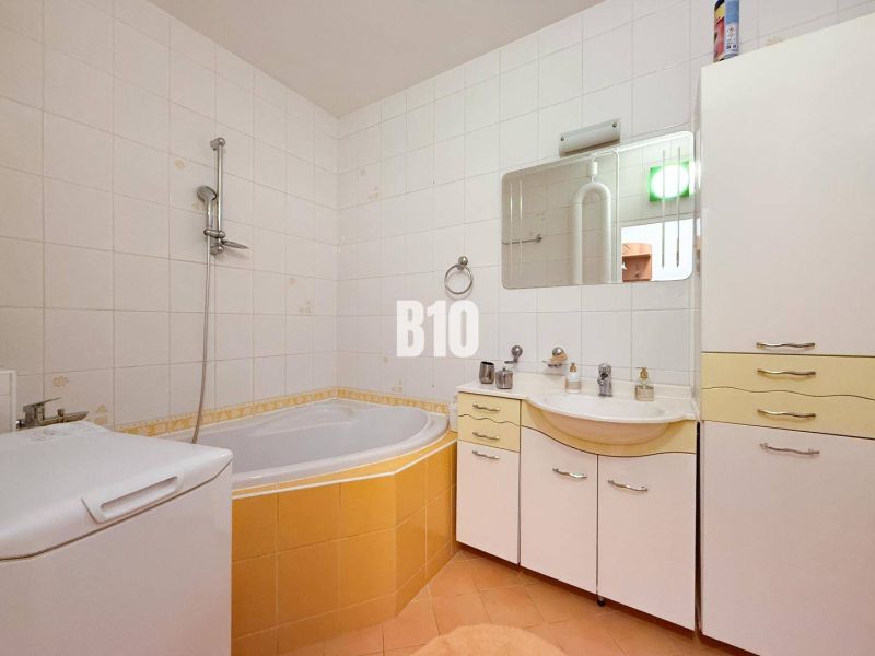Spacious bathroom with shower and bathtub, 3-room apartment with light tiles.