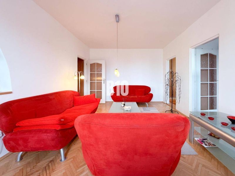 Living room with red sofas and a wooden decor floor in a three-room apartment.