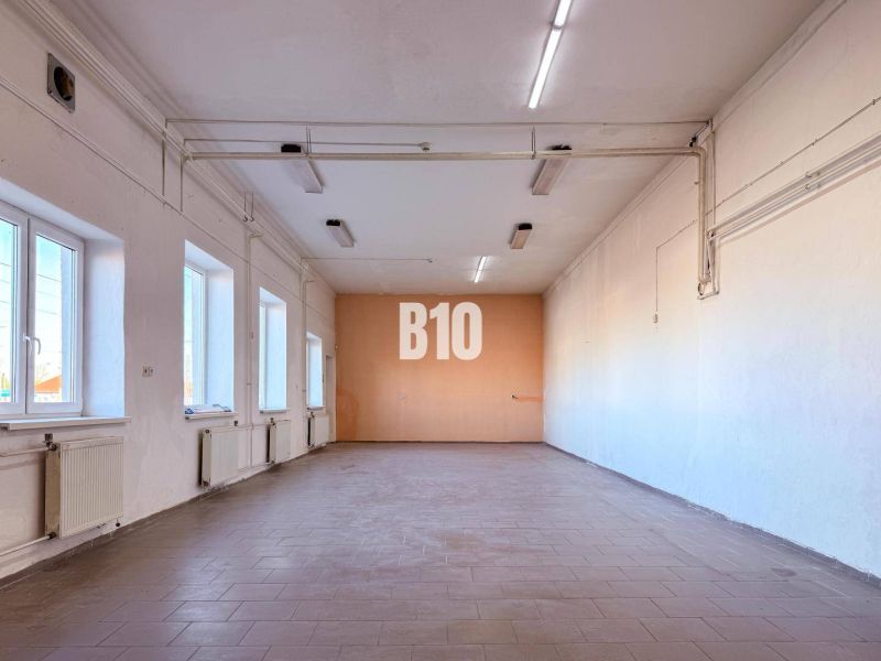 Interior of commercial premises with windows, radiators, and white walls.