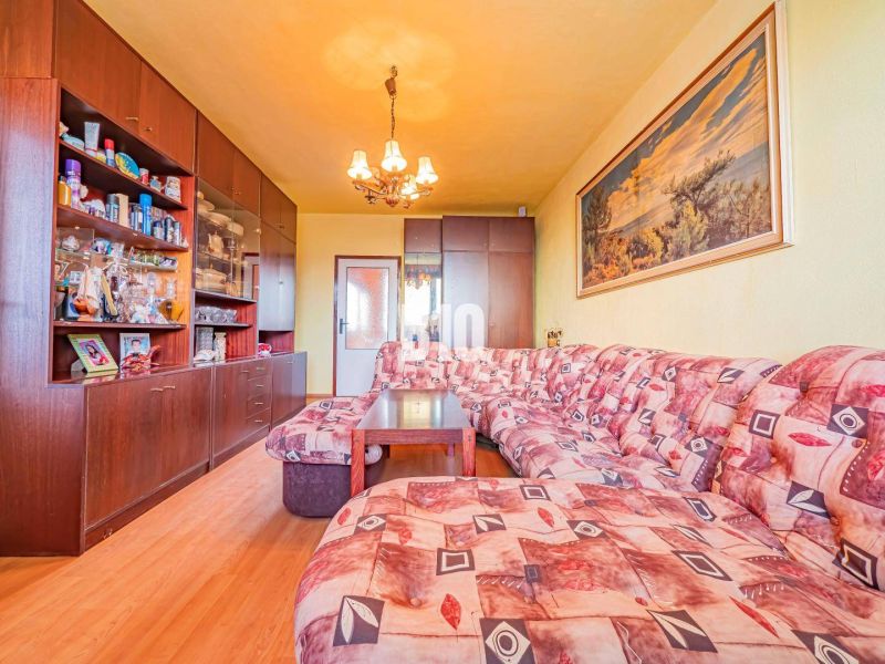 Living room in a 3-room apartment with a wooden decor floor and a corner sofa.