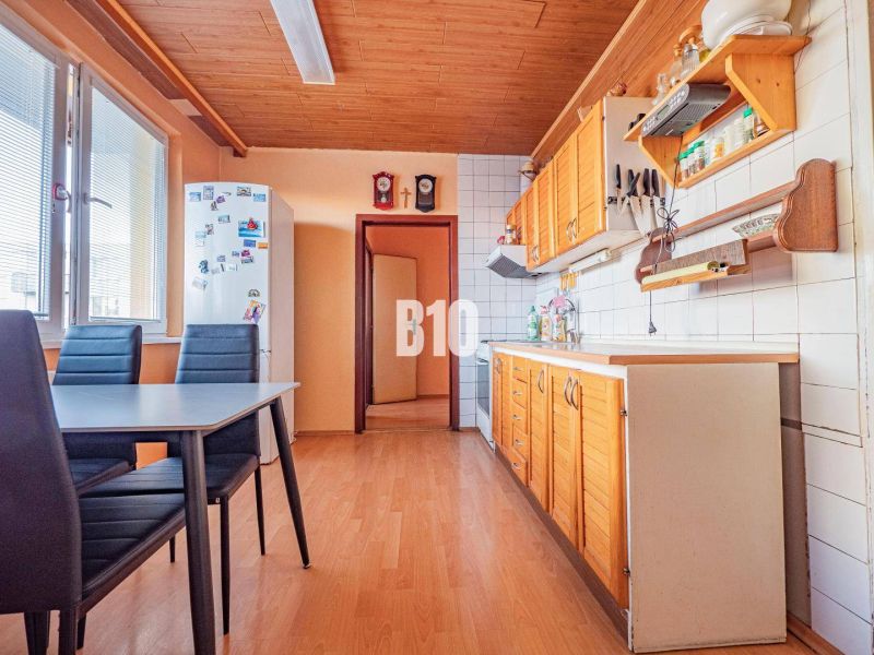 A kitchen in a 3-room apartment with a wooden decor floor and a dining table.