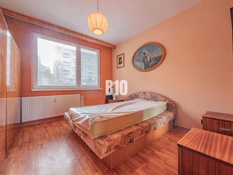 A bedroom in a 3-room apartment with a bed, a wardrobe, and a wooden decor floor.