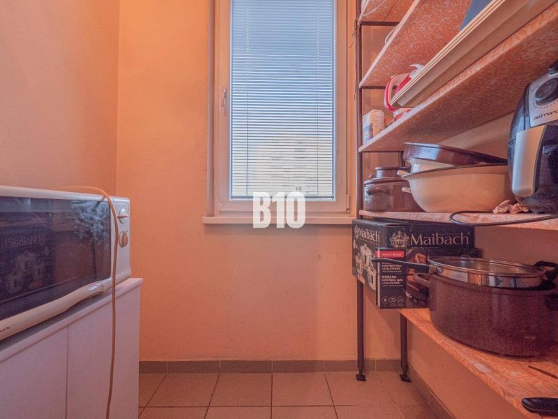 Pantry in a 3-room apartment with shelves, kitchen appliances, and storage boxes.