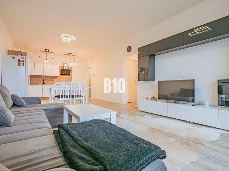 Living room with kitchen, white furniture, sofa and floor with wood decor.