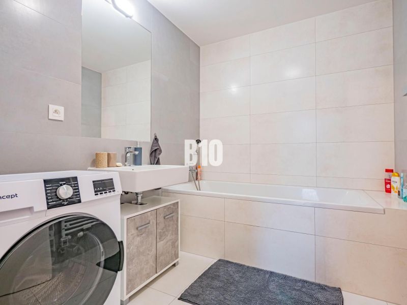 Bathroom with a bathtub, sink, and washing machine in a 3-room apartment.