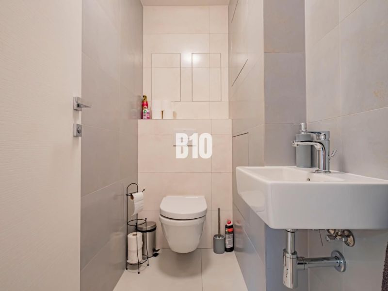 A bathroom in a 3-room apartment with simple light tiles and sanitary equipment.
