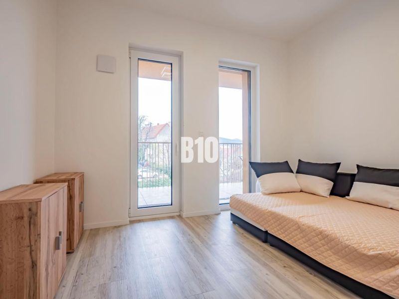 A room in a 3-room apartment with a sofa, cabinets, and a floor with a wooden decor.