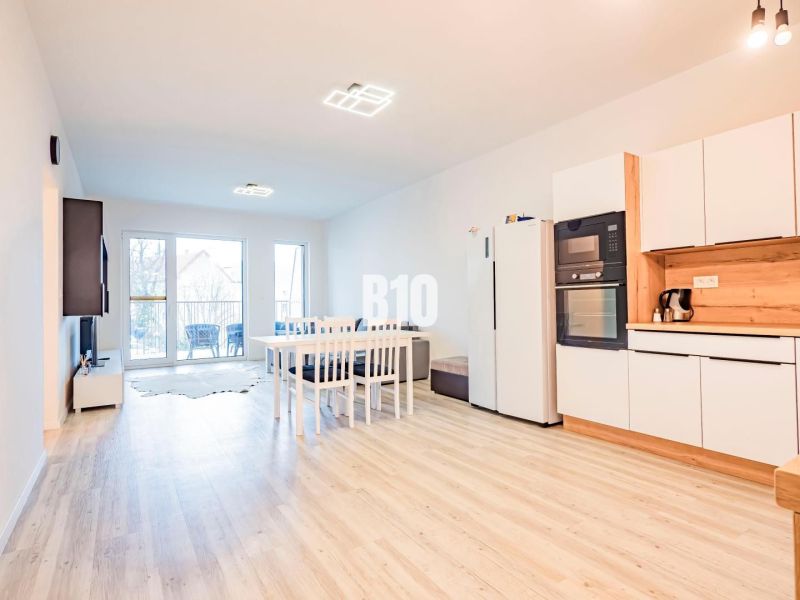 A kitchen in a 3-room apartment with a wooden decor floor and a dining table.