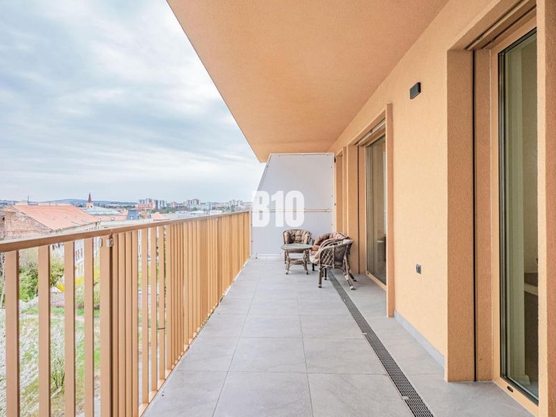A balcony of a 3-room apartment in Nitra with a view of the city and outdoor seating.