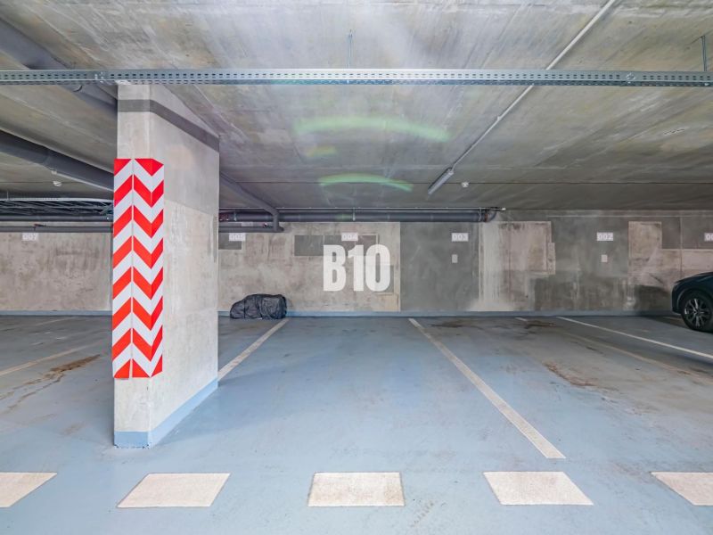 Underground parking in Nitra with marked parking spaces and concrete pillars.