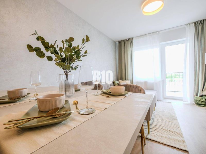 Dining table in a 2-room apartment with place settings and decor in light colors.