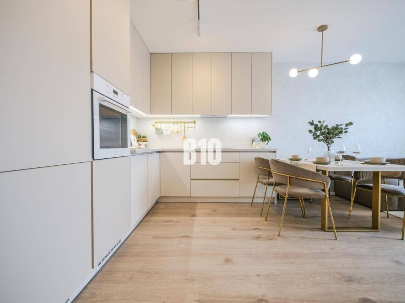 A bright kitchen with a dining table and a wooden decor floor in a two-room apartment.