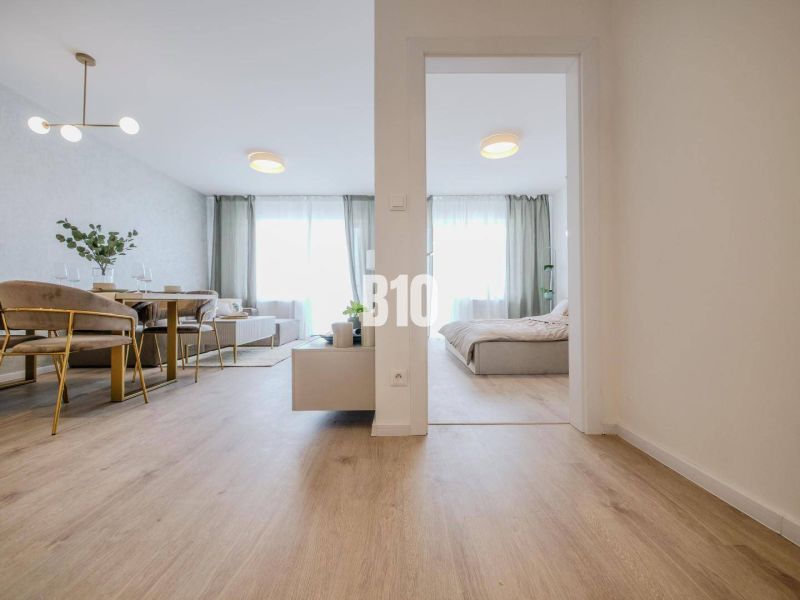Interior of a 2-room apartment with a wooden decor floor, dining table, and bed.