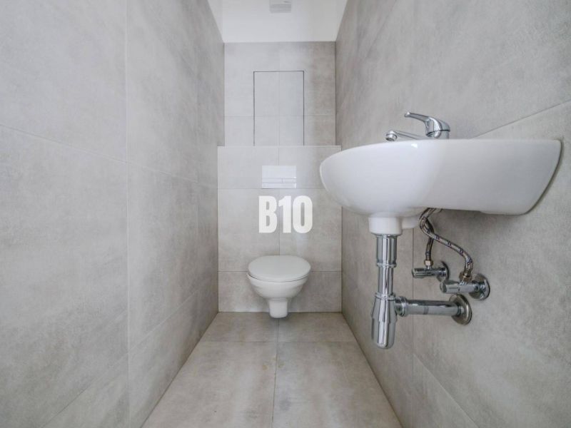 Bathroom with toilet and sink in a 3-room apartment, light tiles.