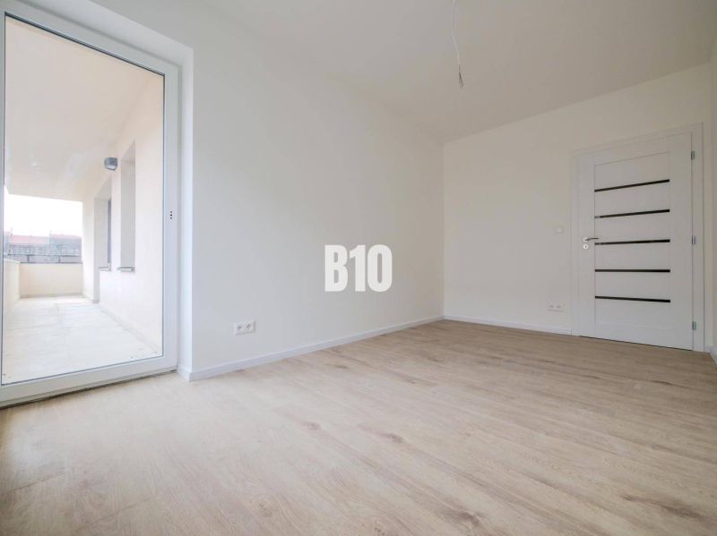 A room with a wooden floor design and large balcony doors in a 3-room apartment.