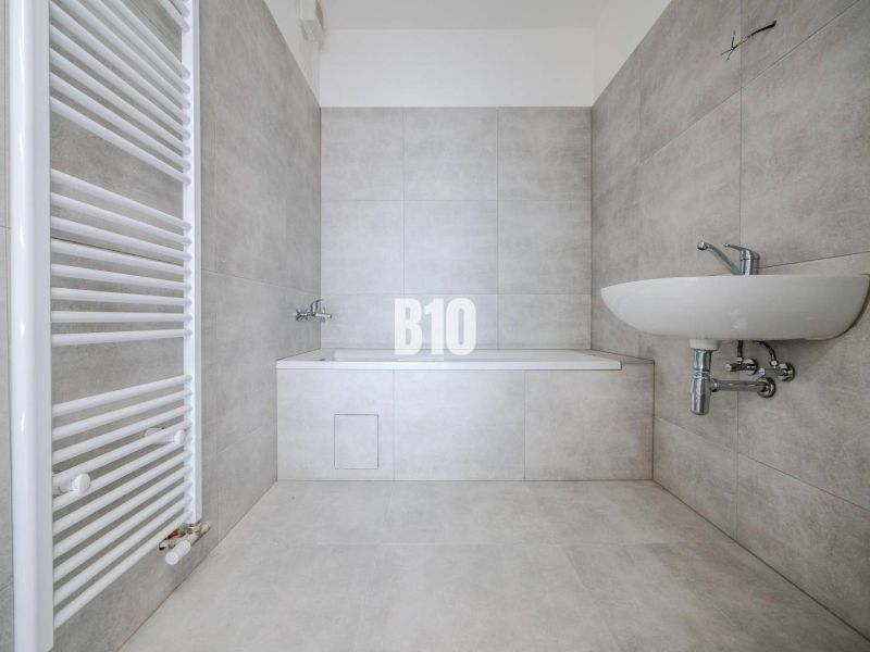 Bathroom with a bathtub and a sink in a 3-room apartment with modern tiles.
