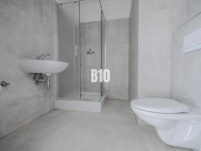 Bathroom with a sink, shower, and toilet in a studio apartment.