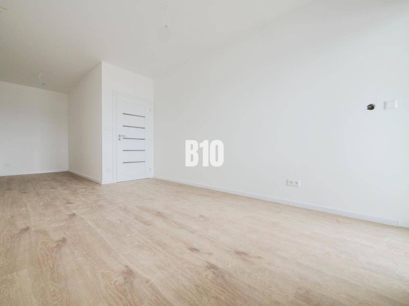Spacious interior with wooden flooring and white walls in a 2-room apartment.