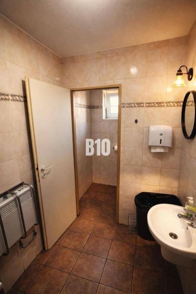 Bathroom with a sink, white soap dispenser, and floor with brown decor in a building.