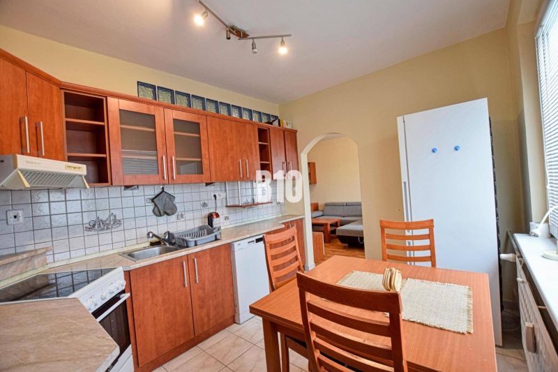 The kitchen of a 3-room apartment with wooden decor cabinets and a dining table.