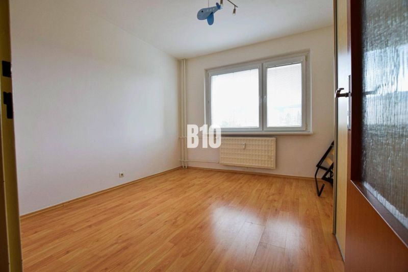 A room in a 3-room apartment with a wooden decor floor and a large window.