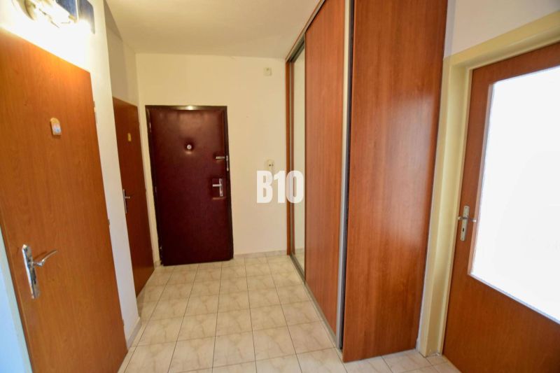 Entrance hall in a 3-room apartment with tiles and wooden built-in wardrobes.