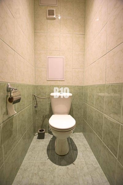 A toilet with tiled walls in a 3-room apartment.