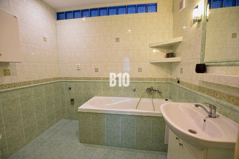 A bathroom with a bathtub and green tiles in a 3-room apartment.