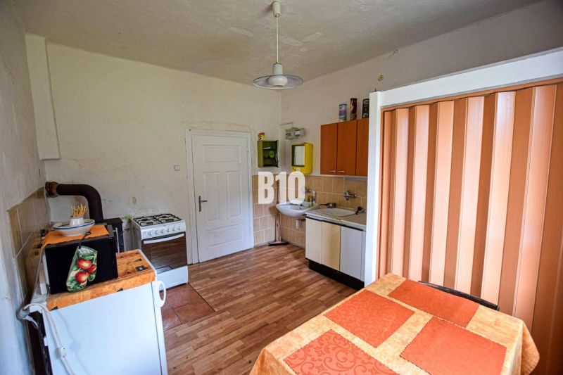 A kitchen in a family house with a tiled stove, a cooker, and a floor with a wooden decor.
