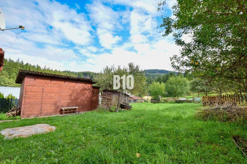 The garden of a family house in Makov with wooden shelters and green trees in the surroundings.