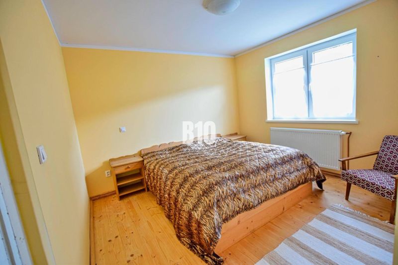 A bedroom with a double bed, wooden furniture, and a wooden decor floor in a family house.