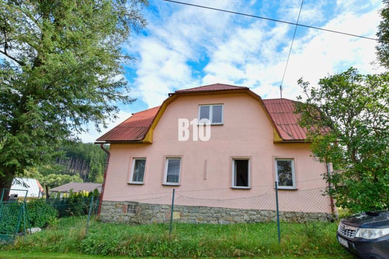 A family house in Makov with a stone foundation and a red roof surrounded by greenery.