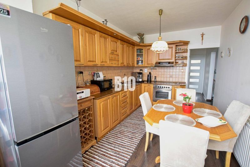 A kitchen in a 3-room apartment with a corner unit and a floor with a wood decor.