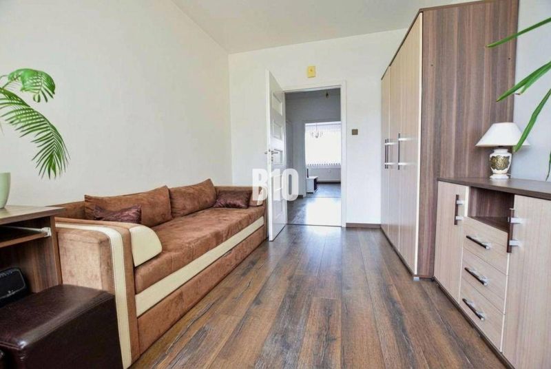A sofa, a wooden-decor floor, and a cabinet in a 3-room apartment.