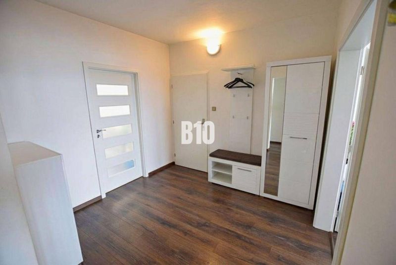 The entrance hall of a 3-room apartment with a wooden decor floor, a wardrobe, and a coat rack.
