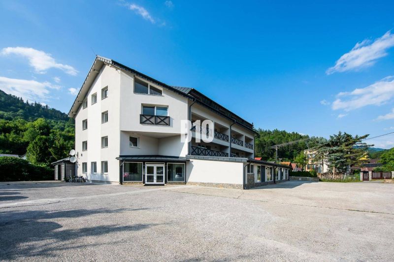 A building in Terchová with a clear sky and green hills in the background.