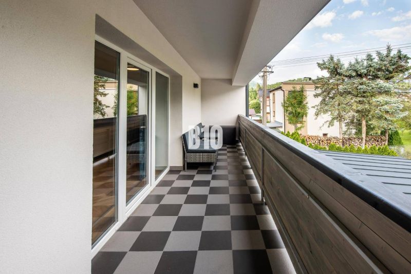 A balcony in a one-room apartment in Terchová with tiles, view of greenery and buildings.