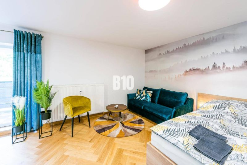 1-bedroom apartment with a wooden decor floor, a sofa, and a nature-themed photo wallpaper.