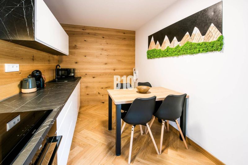 A kitchen in a studio apartment with a wood-patterned floor and art on the wall.