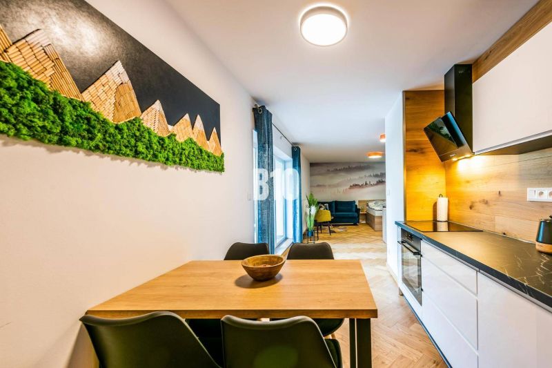 Interior of a 1-room apartment with a wooden decor floor, decoration, and a kitchenette.