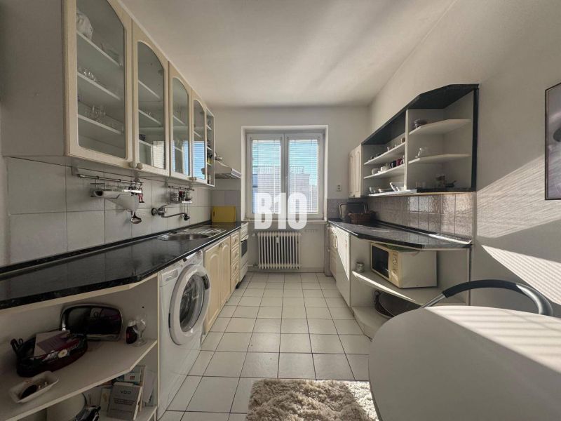 A kitchen in a 2-room apartment with white cabinets and a black countertop.