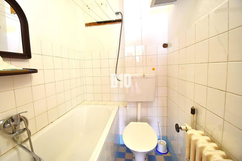 A bathroom in a family house with a bathtub, toilet, and tiled walls.