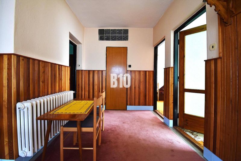 Hallway in a family house with wooden paneling, a table, and a chair.